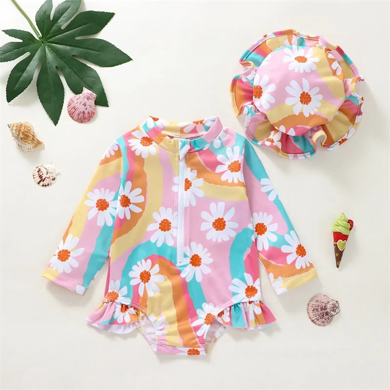 Baby girl wearing Baby Bubble UV swimsuit with long sleeves and matching hat, sun protection, zipper closure, in a playful setting.